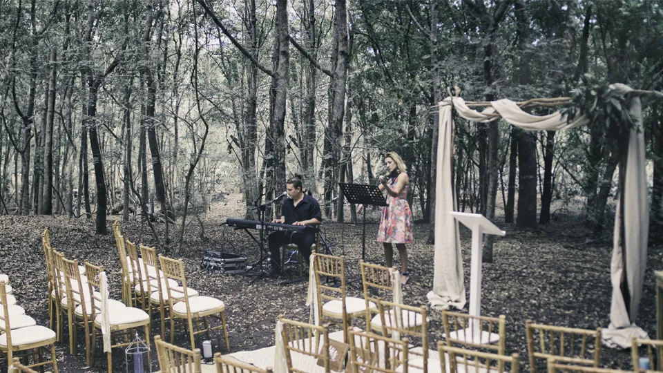 Cérémonie de mariage en plein air : le duo Your Event Animation au piano et au chant devant l'arche et les chaises des invités