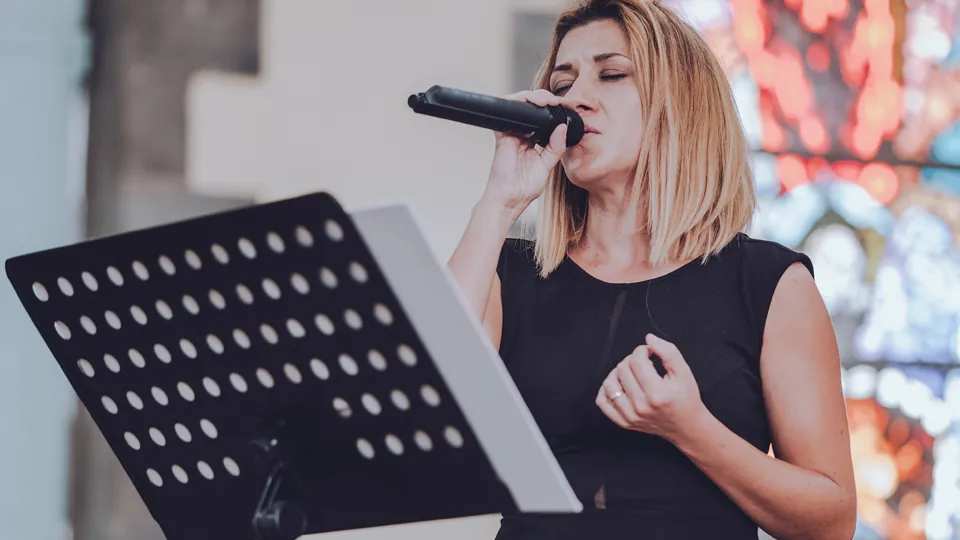 Chant au micro lors d'une cérémonie religieuse de mariage, devant le vitrail de l'église